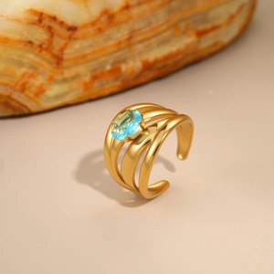 Modern 18K gold-plated irregular hollow ring with oval blue zircon on warm stone base