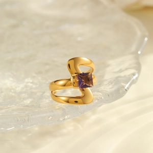 Detail of irregular S-shaped gold-plated stainless steel ring with square purple zircon