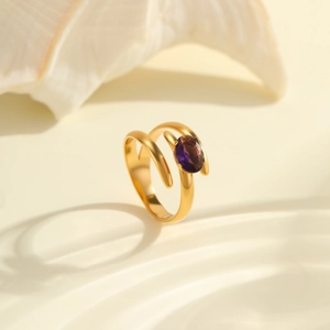 Detail of an irregular gold-plated spiral ring with an oval purple zircon on a shell