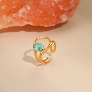 Macro detail of layered gold-plated wave ring featuring a central blue oval zircon gemstone