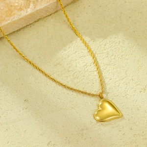 Detalle de collar con colgante de corazón y cadena de cuerda trenzada bañada en oro