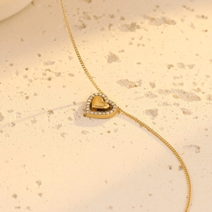 Detalle macro de collar de doble corazón chapado en oro 18K con pavé de circonitas