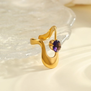 Detailed macro view of irregular gold wavy ring featuring a sparkling purple zircon inlay