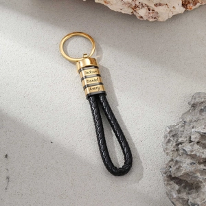 Macro shot of custom engraved gold names on braided black leather keyring loop
