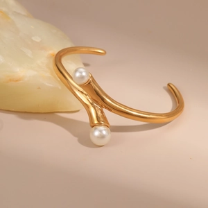 Detail shot of bifurcated gold cuff bracelet with white pearls on a minimalist stone