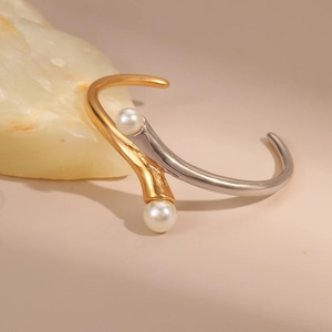 Detail view of two-tone gold and silver C-shape bracelet with elegant white pearls