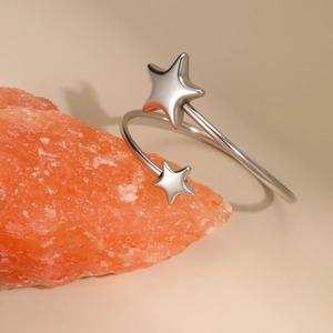 Polished silver stainless steel open star cuff bracelet displayed on orange stone