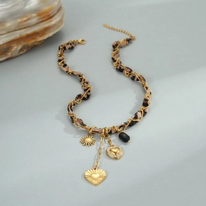 Detail of leopard print fabric woven gold chain necklace with sun and heart charms