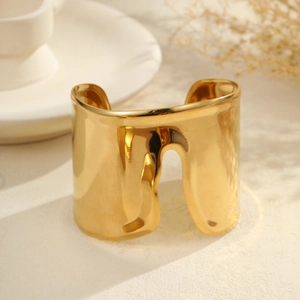 Detalle del brazalete ancho dorado con textura de lava fundida irregular y diseño ondulado