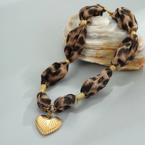 Leopard print fabric necklace featuring a textured gold heart pendant on natural stones