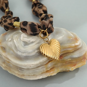 Leopard print fabric necklace featuring a polished heart pendant on a shell background