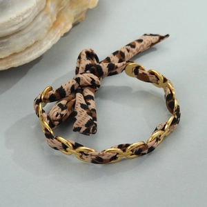 Detail of 18K gold plated wide cuff bangle with leopard print ribbon and bow knot