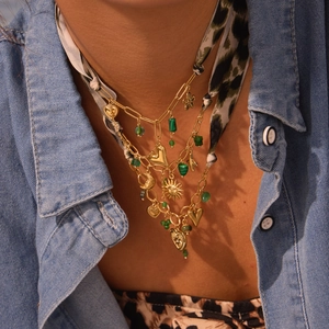 Gelaagde gouden kettingset met hart zon hangers en groene kralen op een panterprint decor