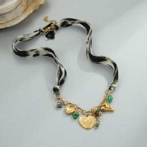 Detailweergave van de luipaardprint lintketting met gouden harthangers en groene kralen