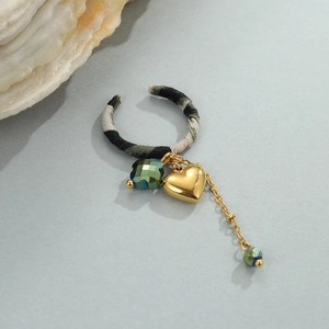 Detail van met stof omwikkelde ring met gouden hartbedeltje en groene kristallen
