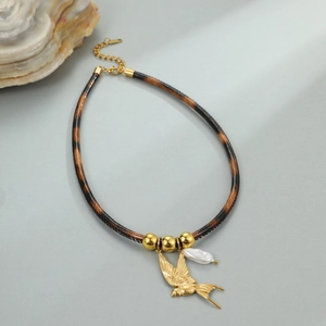 Detail van luipaardprint leren ketting met goudkleurige vogel en barokke parel