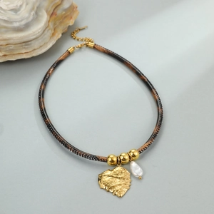 Detail van de luipaardlederen ketting met gouden hart hanger en barokke parel druppel