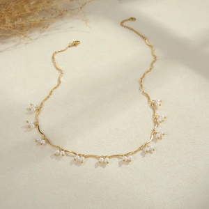 Elegant gold Y-shaped stainless steel necklace with faux pearls on a beige background