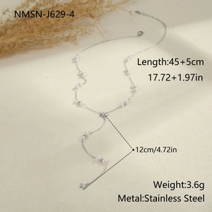 Detail of Y-shaped stainless steel necklace with faux pearls and star pendants on beige surface