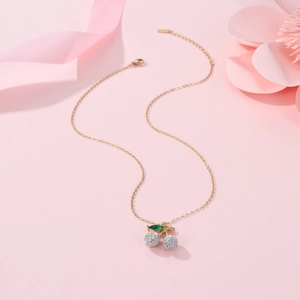Detailed close-up of a 18K gold cherry pendant necklace with sparkling crystal inlay