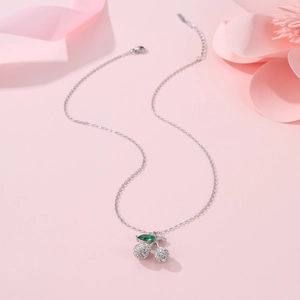 Detail of cherry pendant necklace with green leaf gemstone and sparkling white crystals