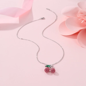 Detail of pink crystal cherry pendant with green leaf on 18K gold stainless steel chain