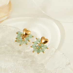 Detailed view of gold heart stud earrings with light green beads on ice-cracked texture