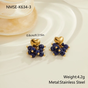 Detailed macro view of gold heart stud earrings with blue stone cluster on a tray