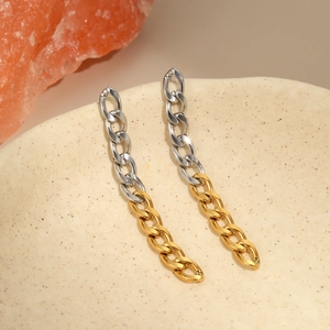 Detail van tweekleurige goud en zilveren ketting oorbellen op een keramische schaal