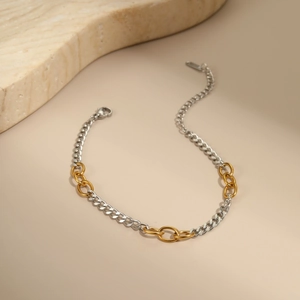 Detail van tweekleurige goud- en zilveren ketting met karabijnsluiting op een stenen achtergrond