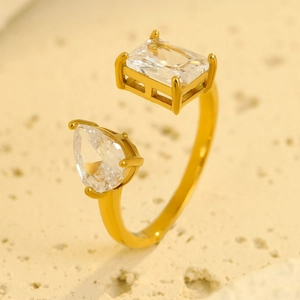 Dettaglio macro di un anello aperto dorato con zirconi rettangolari e a goccia