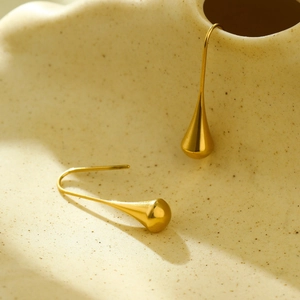 Vue macro détaillée de boucles d'oreilles goutte dorées avec une finition poli miroir