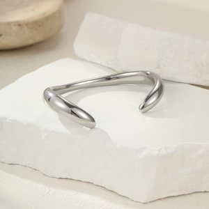 Détail d'un bracelet jonc argenté ondulé en acier inoxydable à texture martelée sur pierre