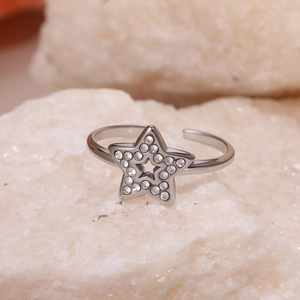 Macro shot of silver star-shaped ring with pavé rhinestones on natural stone