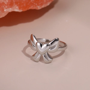 Detailed macro view of silver bow ring with heart center on smooth stone background