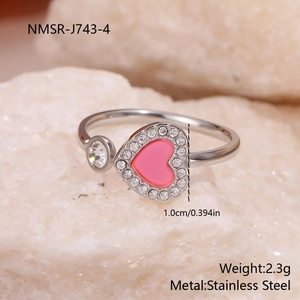 Detail view of pink heart stainless steel ring with micro-pave diamonds on white stone