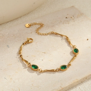 Detail van een verstelbare gouden rvs armband met drie groene ovale zirkonia's