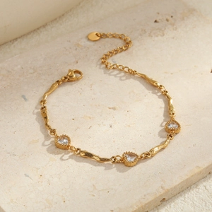 Detail van een gouden hartjesarmband met zirkonia op een zandstenen voetstuk
