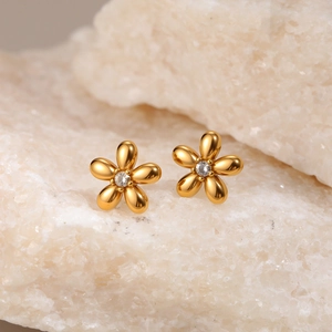 Detailed close-up of golden floral stud earrings with sparkling central zircon inlay