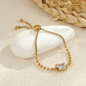 Macro detail of gold adjustable bead bracelet featuring a rectangular zircon stone