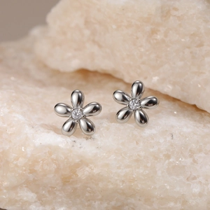 Macro view of silver flower stud earrings with central cubic zirconia on stone