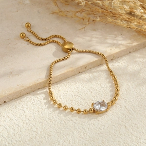 Detail of adjustable gold bead chain bracelet with central round zircon on stone tray