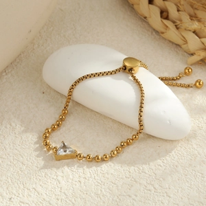 Macro detail of gold stainless steel bracelet with a triangle zircon stone and bead chain