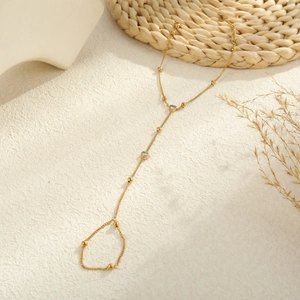 Elegant gold hand harness featuring two heart-shaped zircon stones on a warm textured backdrop