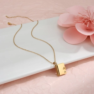 Detailaufnahme der goldenen Briefumschlag-Halskette mit Herz-Motiv und feiner O-Kette