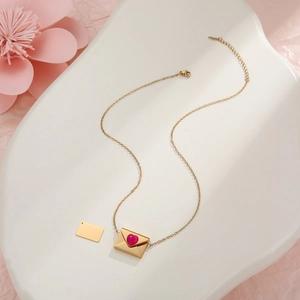 Makroansicht der goldenen Umschlag-Halskette mit rosa Herz und Metalleinlage