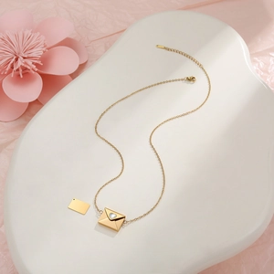 Detail der 18k Gold Herz-Umschlag-Halskette mit Zirkon auf romantischem rosa Hintergrund