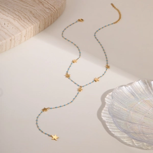 Detalle de collar en Y dorado con cuentas azul claro y pequeños colgantes de estrella