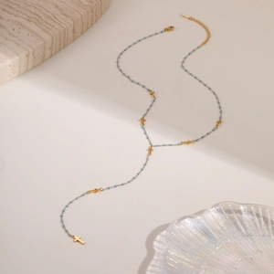 Elegante collar en Y dorado con cuentas azules y colgantes de cruz en bandeja chic