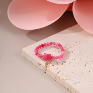 Detail of pink natural stone beaded ring with rectangular gem on a stone display